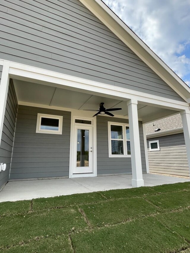 entrance to property featuring a yard, a patio area, and ceiling fan