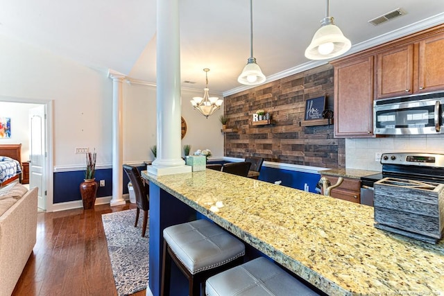 kitchen featuring appliances with stainless steel finishes, decorative columns, dark hardwood / wood-style flooring, hanging light fixtures, and crown molding