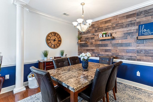 dining area with ornate columns, crown molding, an inviting chandelier, and dark hardwood / wood-style flooring