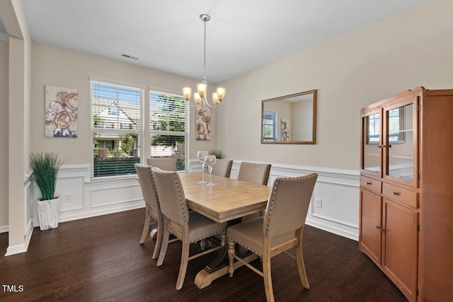 dining area with dark hardwood / wood-style flooring and an inviting chandelier