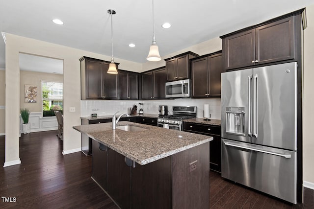 kitchen featuring stainless steel appliances, sink, light stone countertops, dark hardwood / wood-style floors, and hanging light fixtures