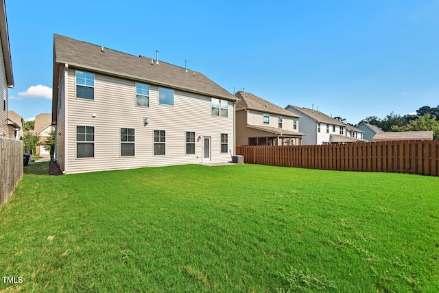 rear view of house with central AC unit and a yard