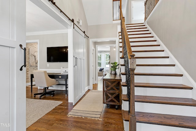 stairway with crown molding, hardwood / wood-style flooring, lofted ceiling, and a barn door