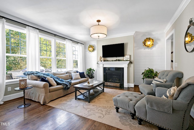 living area with crown molding, a fireplace with flush hearth, plenty of natural light, and wood finished floors