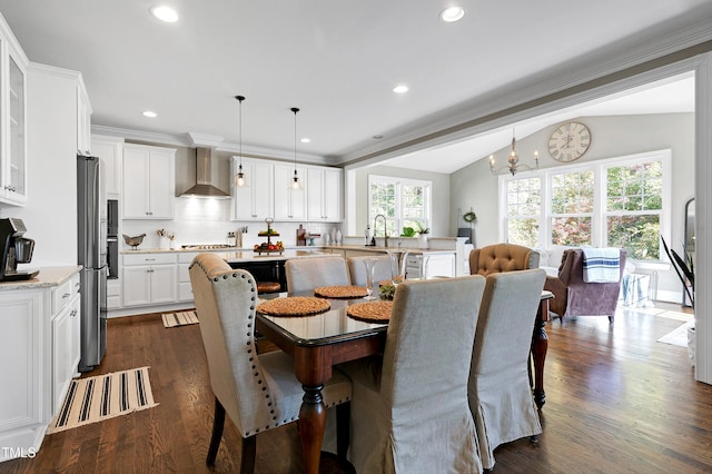 dining space featuring lofted ceiling, dark hardwood / wood-style floors, ornamental molding, sink, and an inviting chandelier