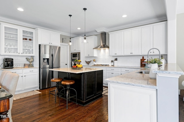 kitchen with a kitchen breakfast bar, wall chimney exhaust hood, tasteful backsplash, a sink, and stainless steel appliances