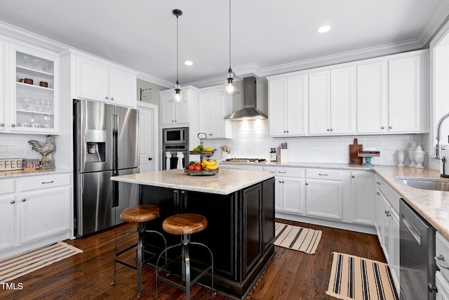 kitchen with wall chimney range hood, white cabinets, a sink, stainless steel appliances, and backsplash