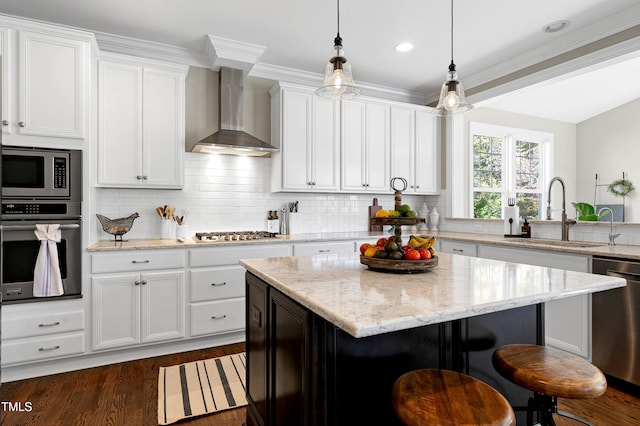 kitchen featuring stainless steel appliances, wall chimney exhaust hood, sink, and a kitchen island