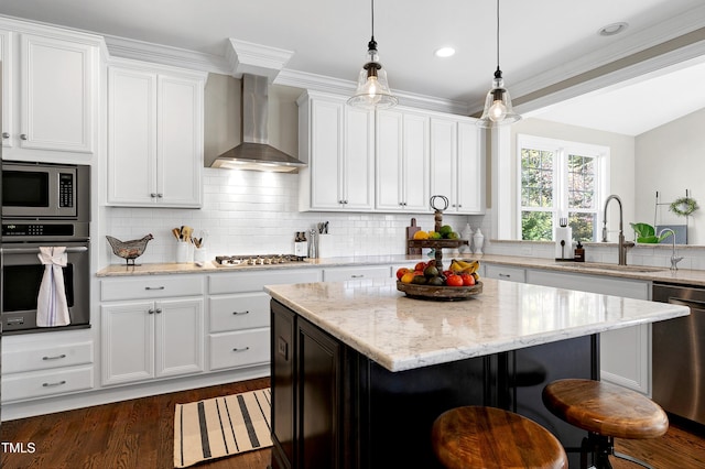 kitchen with appliances with stainless steel finishes, a breakfast bar, a sink, wall chimney exhaust hood, and decorative backsplash