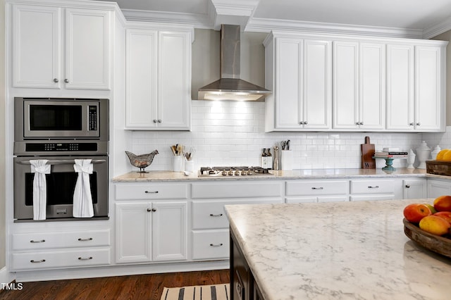 kitchen with white cabinets, light stone countertops, appliances with stainless steel finishes, and wall chimney exhaust hood