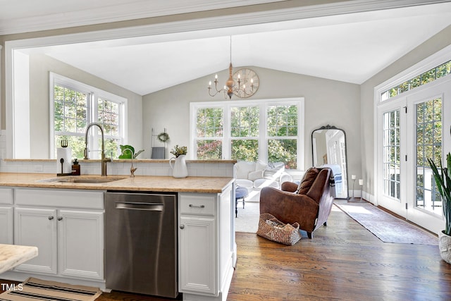 kitchen featuring stainless steel dishwasher, a sink, lofted ceiling, an inviting chandelier, and dark wood-type flooring