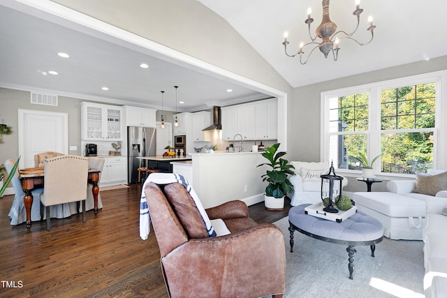 living room featuring sink, lofted ceiling, dark wood-type flooring, crown molding, and a chandelier