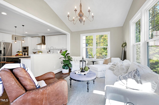 living room with lofted ceiling, hardwood / wood-style floors, a chandelier, crown molding, and sink