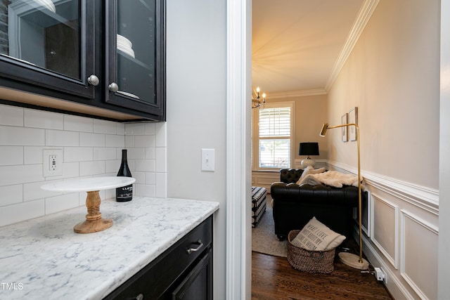 kitchen featuring light stone countertops, backsplash, ornamental molding, a chandelier, and dark hardwood / wood-style floors