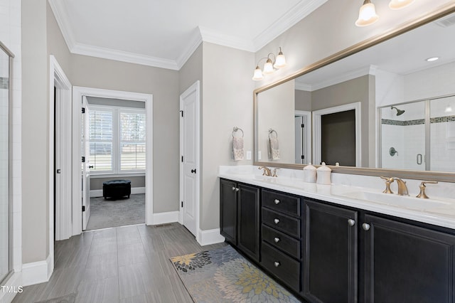 bathroom with a shower with door, vanity, and ornamental molding