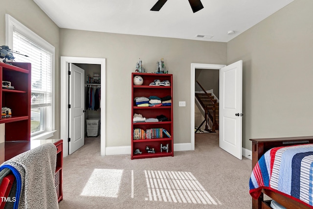 bedroom with carpet floors, visible vents, multiple windows, and a walk in closet