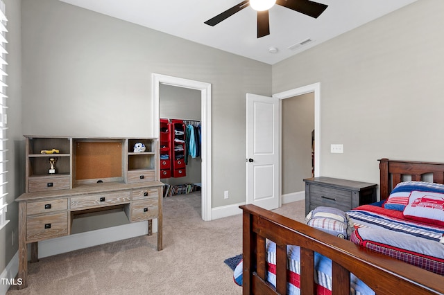 carpeted bedroom featuring ceiling fan and a walk in closet