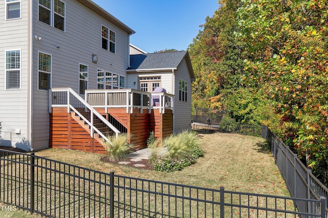 rear view of house with a lawn, a fenced backyard, a wooden deck, and stairway