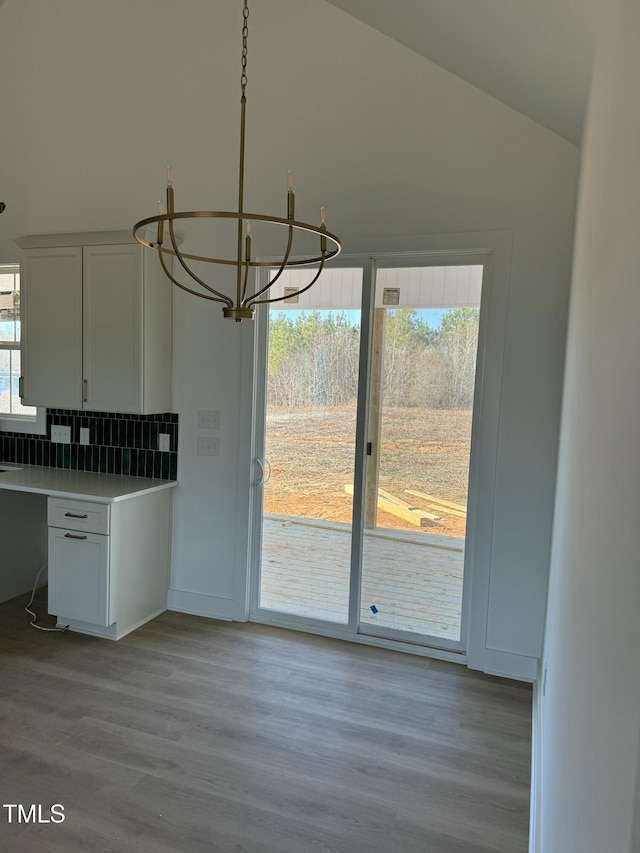 kitchen with lofted ceiling, a wealth of natural light, backsplash, and wood finished floors