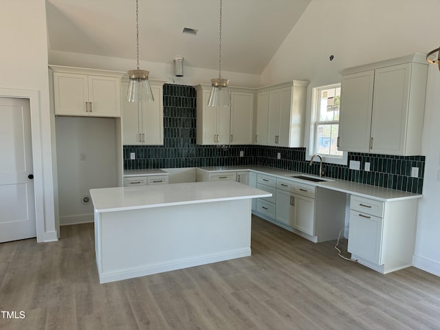 kitchen with light wood-style flooring, a center island, a sink, and backsplash