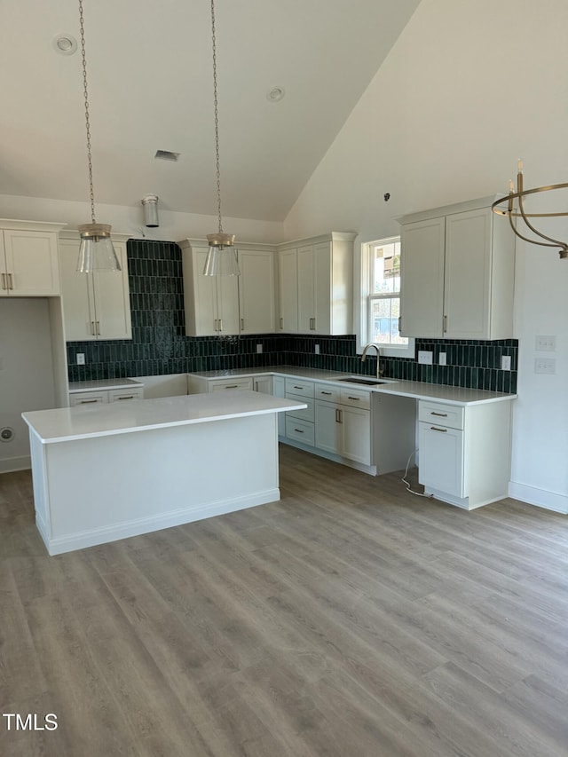 kitchen with light wood finished floors, backsplash, a sink, and a center island