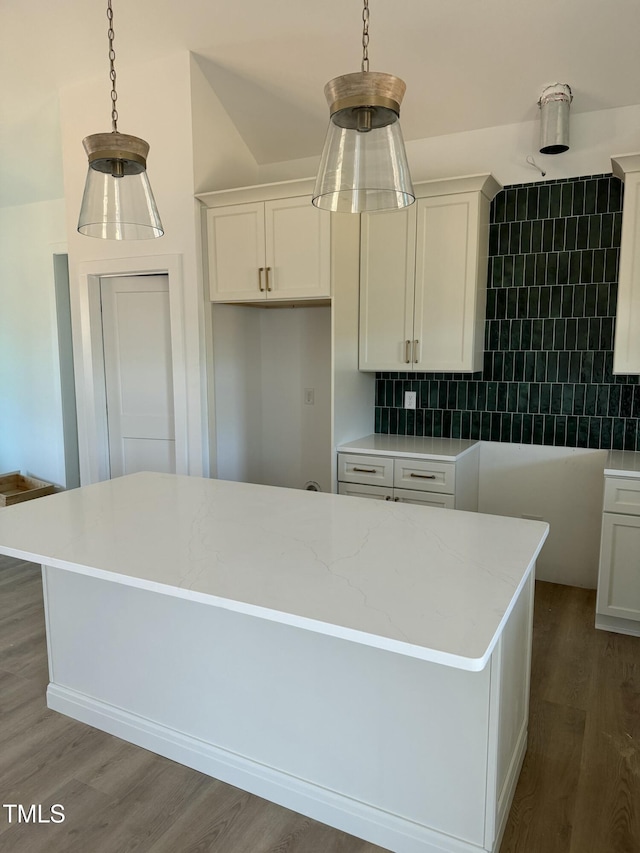 kitchen with hanging light fixtures, a kitchen island, white cabinets, and wood finished floors