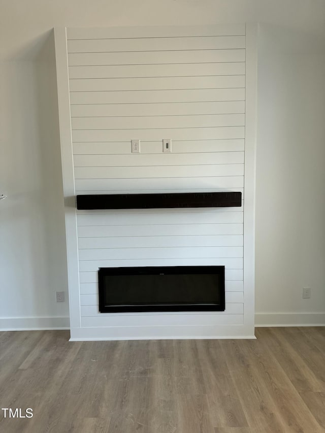 interior details featuring a large fireplace, baseboards, and wood finished floors