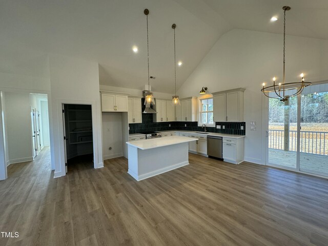 kitchen with a kitchen island, a sink, white cabinets, wall chimney range hood, and appliances with stainless steel finishes