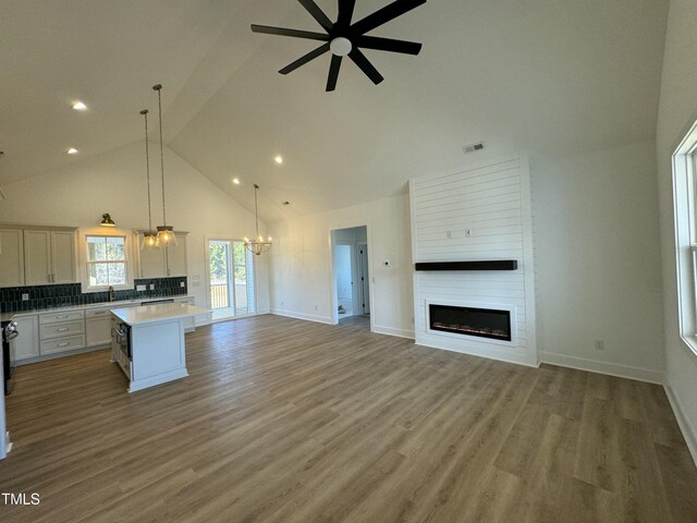 kitchen featuring a large fireplace, visible vents, open floor plan, light countertops, and a center island