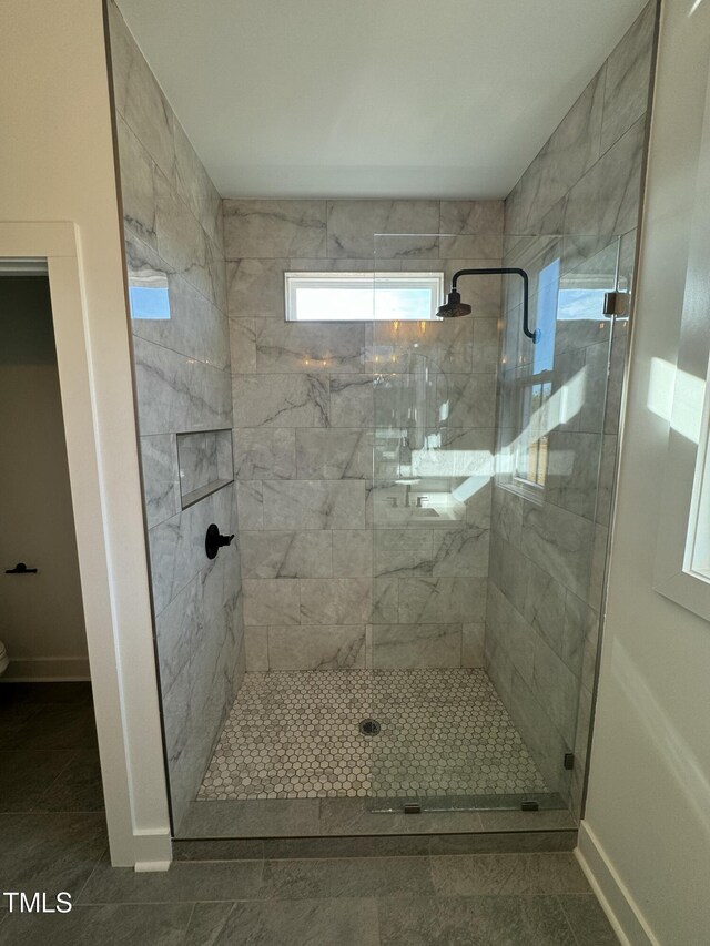 bathroom featuring tile patterned flooring, a shower stall, and baseboards