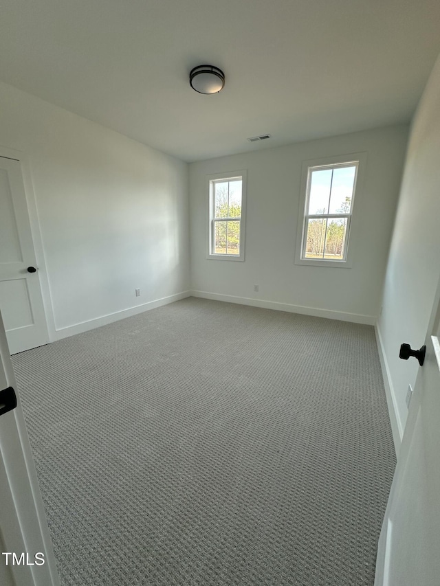 unfurnished room featuring carpet floors, visible vents, and baseboards