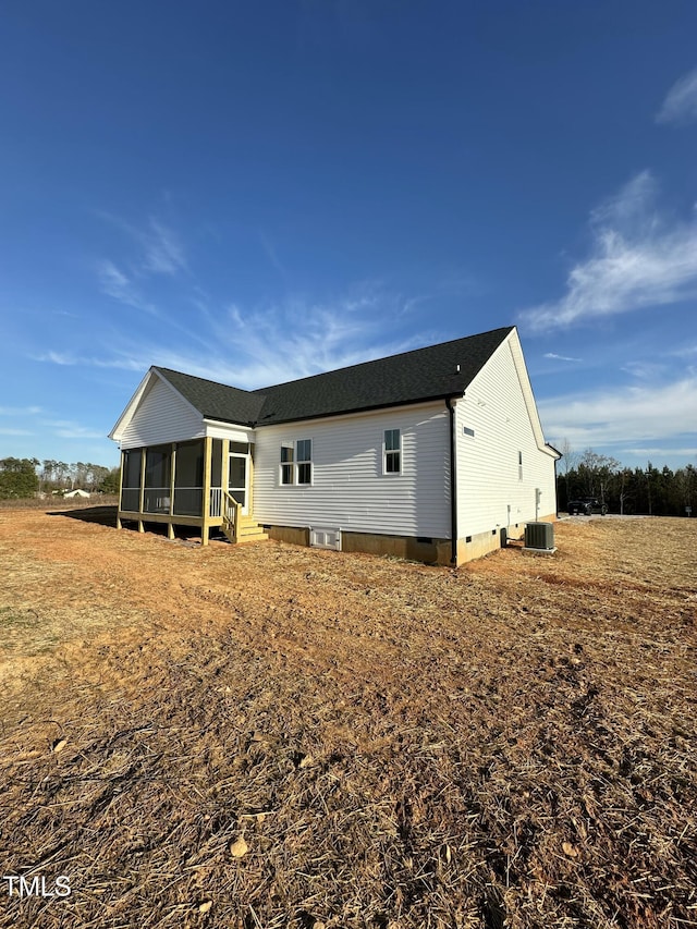 back of house with crawl space, a sunroom, central air condition unit, and a shingled roof