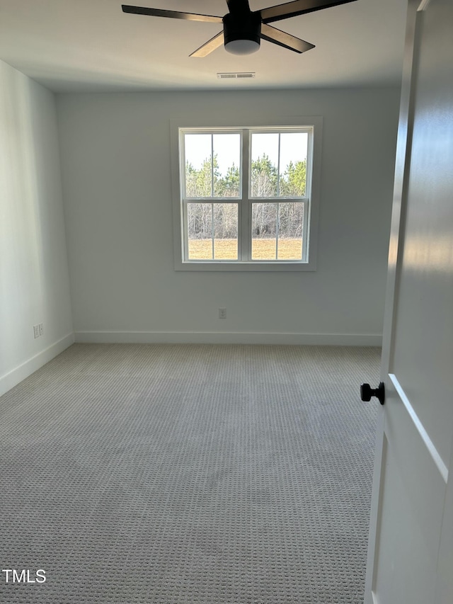 carpeted spare room with visible vents, ceiling fan, and baseboards