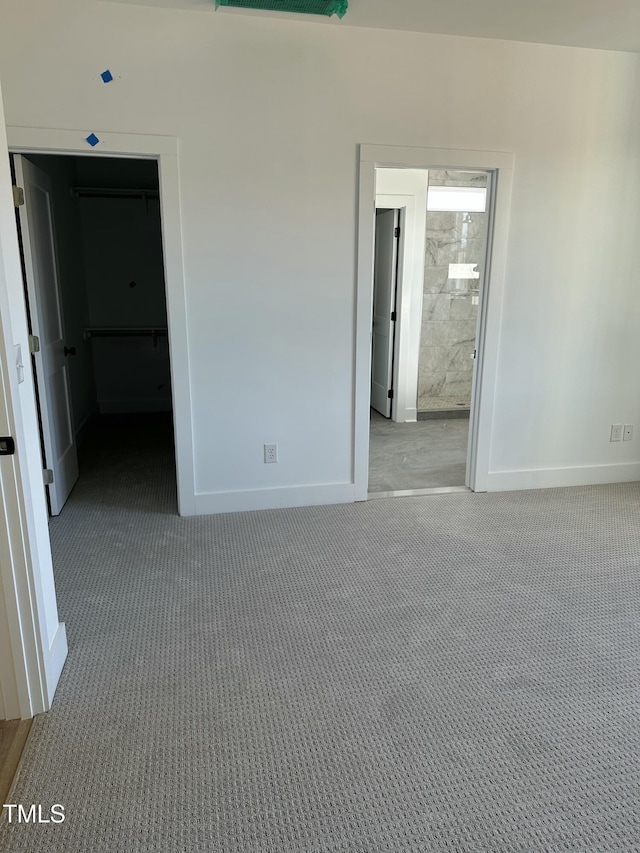 unfurnished bedroom featuring carpet floors, a walk in closet, and baseboards