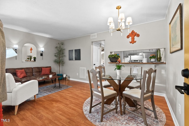 dining space featuring hardwood / wood-style floors, an inviting chandelier, and ornamental molding