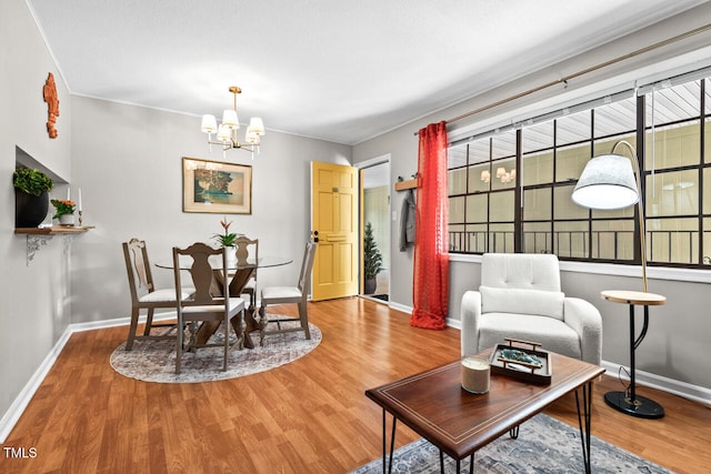 living room featuring wood-type flooring, a textured ceiling, an inviting chandelier, and ornamental molding