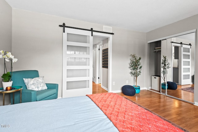 bedroom with a barn door, a closet, and wood-type flooring