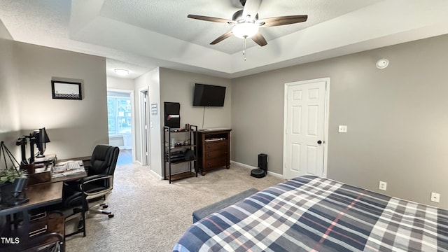 carpeted bedroom with a raised ceiling, a textured ceiling, and ceiling fan