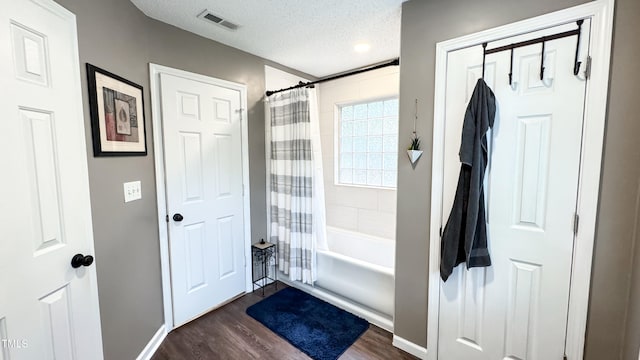 bathroom featuring a textured ceiling, shower / bath combo, and wood-type flooring