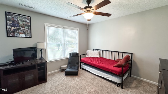 bedroom featuring ceiling fan, light carpet, and a textured ceiling