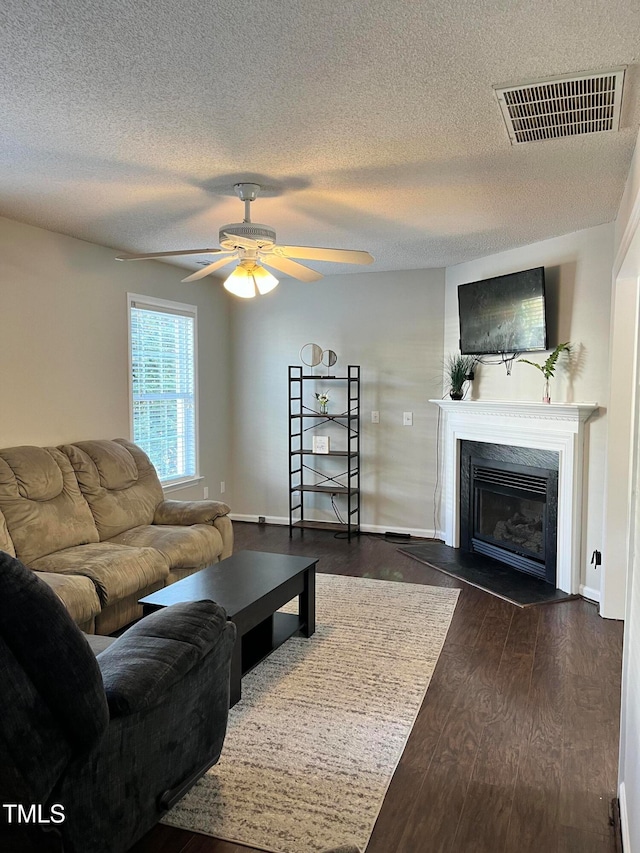 living room with ceiling fan, a textured ceiling, and dark hardwood / wood-style flooring