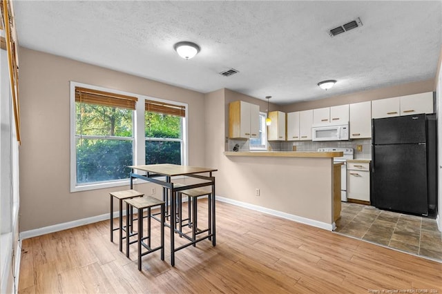 1018 Wood Creek Dr Unit 3, Fayetteville, NC 28314 - kitchen featuring white appliances, light countertops, a peninsula, light wood finished floors, and a textured ceiling