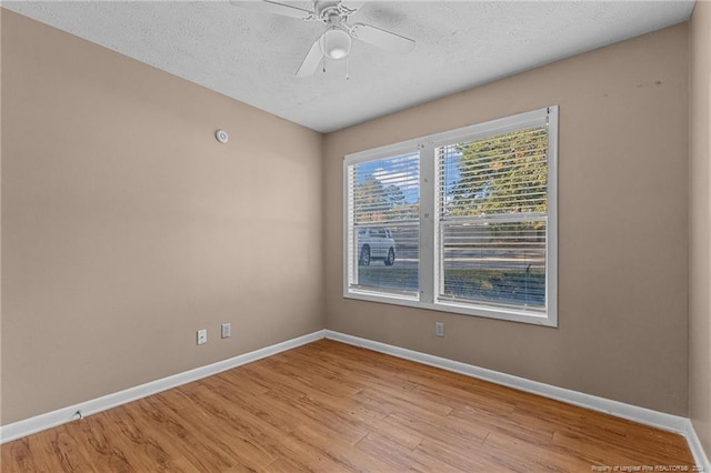 spare room featuring light wood-type flooring, a textured ceiling, and ceiling fan