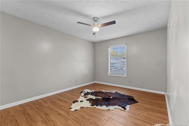 empty room featuring a textured ceiling, hardwood / wood-style flooring, and ceiling fan