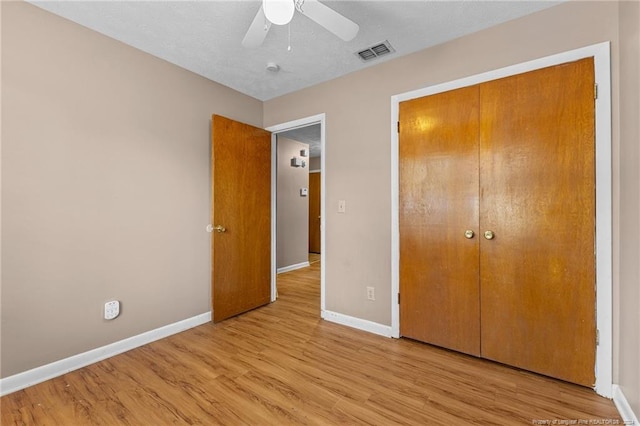 unfurnished bedroom featuring a textured ceiling, light hardwood / wood-style floors, ceiling fan, and a closet