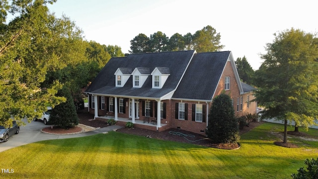 cape cod-style house with covered porch and a front yard