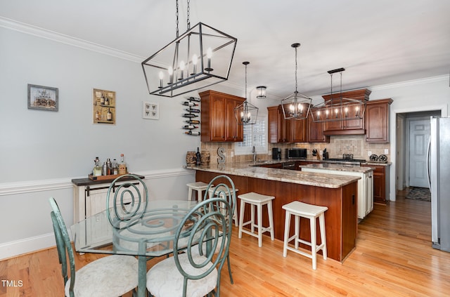 kitchen featuring sink, decorative backsplash, light hardwood / wood-style floors, light stone counters, and kitchen peninsula