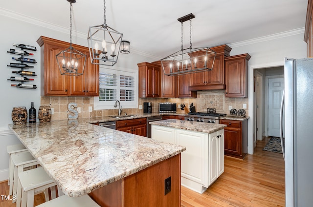 kitchen with stainless steel appliances, crown molding, decorative light fixtures, light hardwood / wood-style flooring, and a breakfast bar area