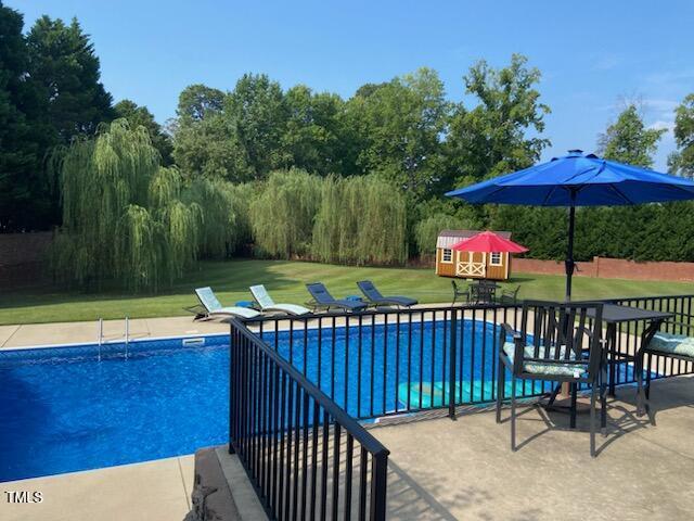 166 Weldon Dr, Clayton, NC 27520 - outdoor pool with a lawn, view of scattered trees, and a patio