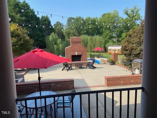 view of patio / terrace featuring an outbuilding and an outdoor brick fireplace